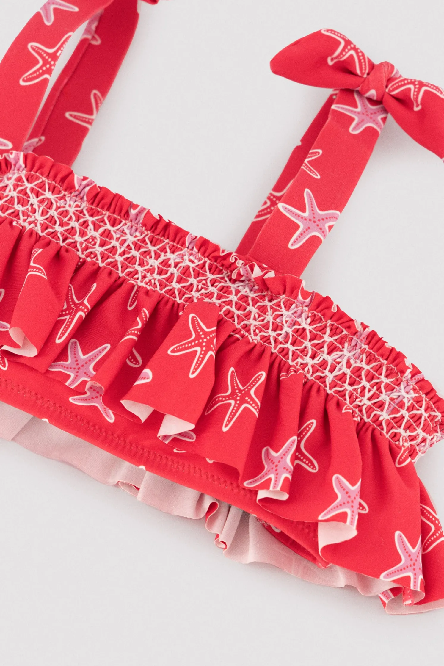 Bikini niña detalles volantes y nido de abeja estampado estrellas marinas rojo